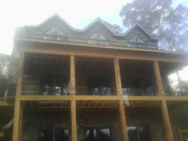 Dormers and porch framing on a large log home under construction — Roof Coating work by our crew in Moore Haven