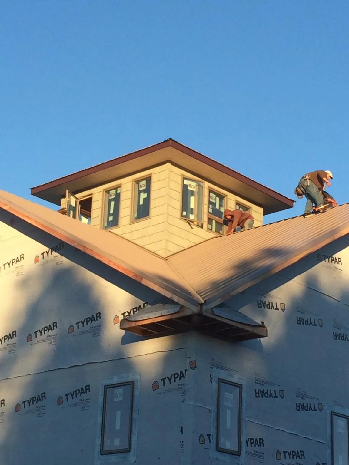 Roofers working around a rooftop cupola on a new metal roof at sunset — Roof Waterproofing in Moore Haven by Roofing Brothers